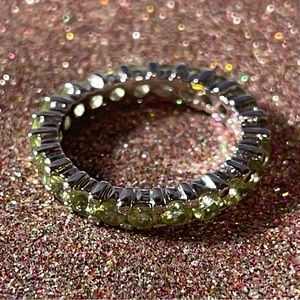Sterling silver ring with green stones all around.
